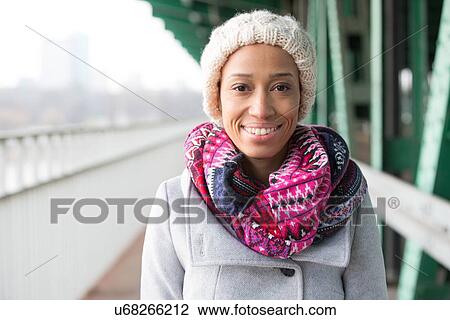 Stock Image - Portrait of happy woman in warm clothing standing outdoors. Fotosearch