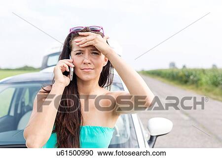 Portrait of tensed woman using cell phone against broken down car on road View Large Photo Image Stock Image - Portrait of tensed woman using cell phone against broken down car on road. Fotosearch