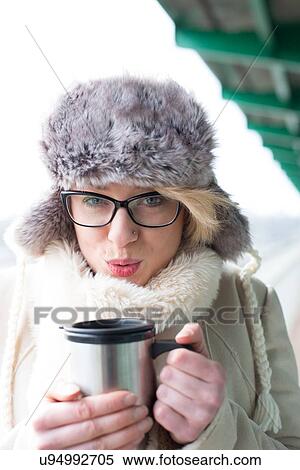 Portrait of woman blowing coffee in insulated drink container during winter View Large Photo Image Stock Photography - Portrait of woman blowing coffee in insulated drink container during winter. Fotosearch