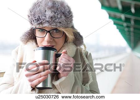 Portrait of woman drinking coffee from insulated drink container during winter View Large Photo Image Stock Photograph - Portrait of woman drinking coffee from insulated drink container during winter. Fotosearch