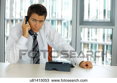 Stock Image - portrait of young confident caucasian businessman talking on phone. Fotosearch