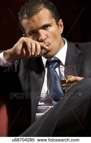 Portrait of young man smoking cigar and holding wineglass View Large Photo Image Stock Photography - Portrait of young man smoking cigar and holding wineglass. Fotosearch