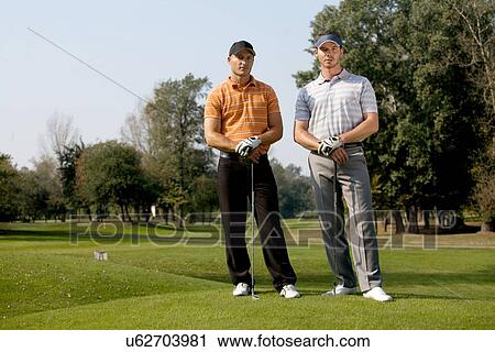 Portrait of young men standing with golf sticks on golf course View Large Photo Image Stock Image - Portrait of young men standing with golf sticks on golf course. Fotosearch