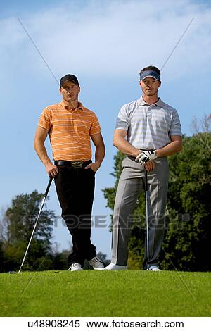 Portrait of young men standing with golf sticks on golf course View Large Photo Image Stock Photography - Portrait of young men standing with golf sticks on golf course. Fotosearch
