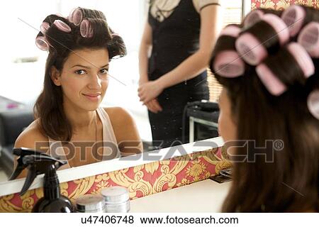 Stock Photo - Portrait of young woman with hair curlers smiling. Fotosearch
