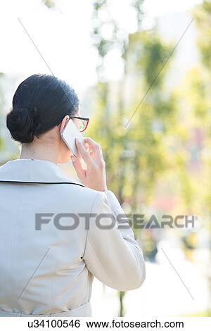 Rear view of businesswoman using cell phone outdoors View Large Photo Image Stock Photograph - Rear view of businesswoman using cell phone outdoors. Fotosearch