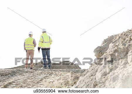 Picture - Rear view of supervisors standing at construction site against clear sky. Fotosearch