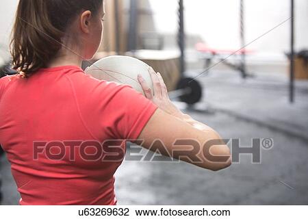 Rear view of woman holding medicine ball in crossfit gym View Large Photo Image Stock Image - Rear view of woman holding medicine ball in crossfit gym. Fotosearch