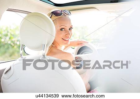 Stock Photo - Rear view portrait of happy woman driving car. Fotosearch