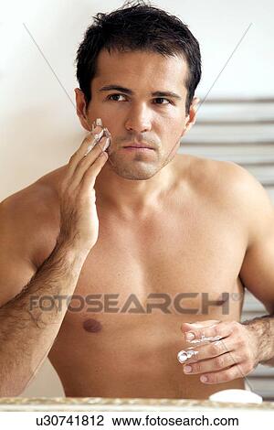 Reflection of young man in mirror applying shaving cream View Large Photo Image Stock Image - Reflection of young man in mirror applying shaving cream. Fotosearch