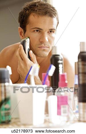 Reflection of young man in mirror shaving with electric shaver View Large Photo Image Stock Image - Reflection of young man in mirror shaving with electric shaver. Fotosearch