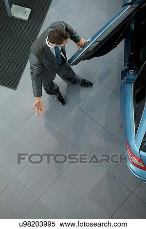 Stock Photography - Salesperson opening door for customers at showroom. Fotosearch