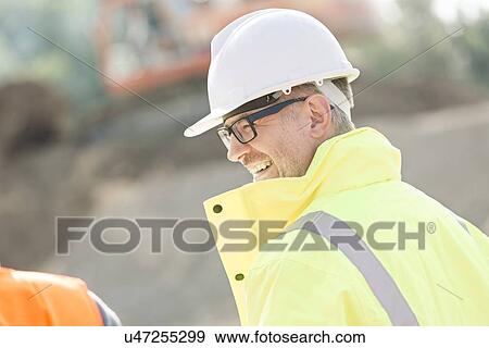 Side view of happy male supervisor at construction site View Large Photo Image Stock Photo - Side view of happy male supervisor at construction site. Fotosearch
