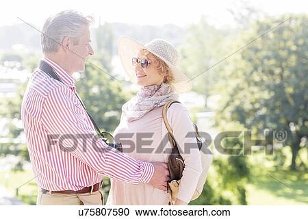Side view of middle-aged couple embracing while looking at each other in park View Large Photo Image Stock Image - Side view of middle-aged couple embracing while looking at each other in park. Fotosearch