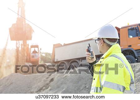 Side view of supervisor using walkie-talkie at construction site against clear sky View Large Photo Image Stock Image - Side view of supervisor using walkie-talkie at construction site against clear sky. Fotosearch