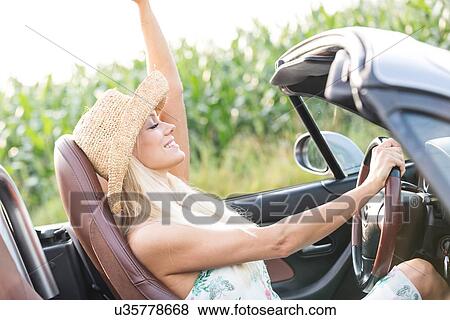 Stock Photo - Side view of woman enjoying ride in convertible outdoors. Fotosearch