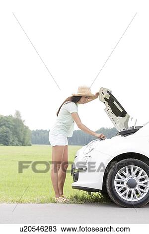 Side view of woman examining broken down car on country road View Large Photo Image Stock Image - Side view of woman examining broken down car on country road. Fotosearch