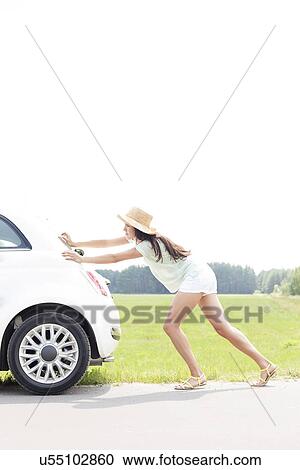 Side view of woman pushing broken down car on country road View Large Photo Image Stock Image - Side view of woman pushing broken down car on country road. Fotosearch
