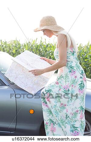 Side view of woman reading map while sitting on convertible View Large Photo Image Picture - Side view of woman reading map while sitting on convertible. Fotosearch