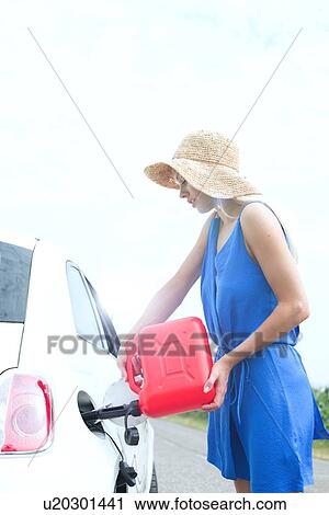 Side view of woman refueling car on country road View Large Photo Image Stock Image - Side view of woman refueling car on country road. Fotosearch