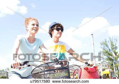 Smiling couple cycling against sky View Large Photo Image Stock Image - Smiling couple cycling against sky. Fotosearch