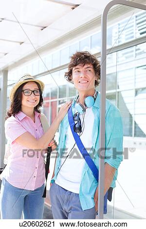 Smiling couple looking away while waiting at bus stop View Large Photo Image Stock Image - Smiling couple looking away while waiting at bus stop. Fotosearch