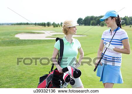 Smiling female golfers talking at golf course View Large Photo Image Stock Photograph - Smiling female golfers talking at golf course. Fotosearch