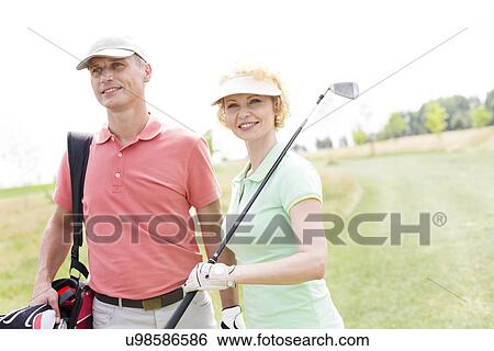 Smiling male and female friends standing at golf course View Large Photo Image Stock Photograph - Smiling male and female friends standing at golf course. Fotosearch