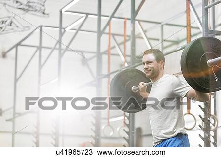 Smiling man lifting barbell at crossfit gym View Large Photo Image Stock Image - Smiling man lifting barbell at crossfit gym. Fotosearch