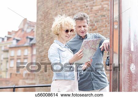 Smiling middle-aged couple reading map in city View Large Photo Image Picture - Smiling middle-aged couple reading map in city. Fotosearch