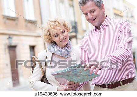 Smiling middle-aged couple reading map in city View Large Photo Image Stock Photograph - Smiling middle-aged couple reading map in city. Fotosearch