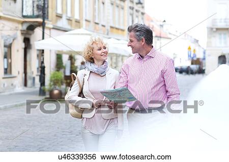 Smiling middle-aged couple with map looking at each other while walking in city View Large Photo Image Stock Photograph - Smiling middle-aged couple with map looking at each other while walking in city. Fotosearch