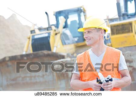 Smiling supervisor looking away at construction site View Large Photo Image Stock Photography - Smiling supervisor looking away at construction site. Fotosearch