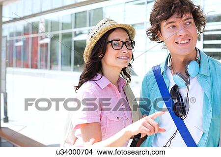 Smiling woman showing something to man while waiting at bus stop View Large Photo Image Picture - Smiling woman showing something to man while waiting at bus stop. Fotosearch