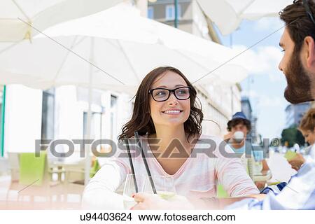 Picture - Smiling woman sitting with man at sidewalk cafe. Fotosearch