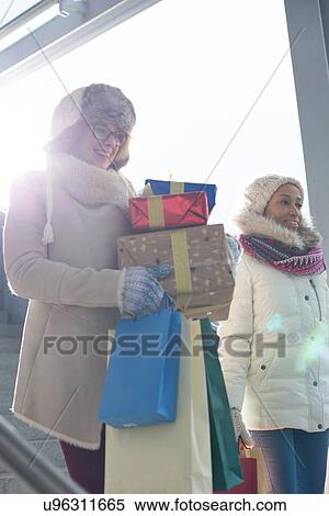 Smiling women with gifts and shopping bags by window during winter View Large Photo Image Stock Photography - Smiling women with gifts and shopping bags by window during winter. Fotosearch