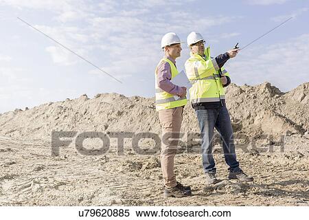 Stock Photography - Supervisor examining construction site against sky. Fotosearch