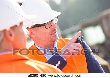 Supervisor showing something to colleague at construction site View Large Photo Image Stock Image - Supervisor showing something to colleague at construction site. Fotosearch