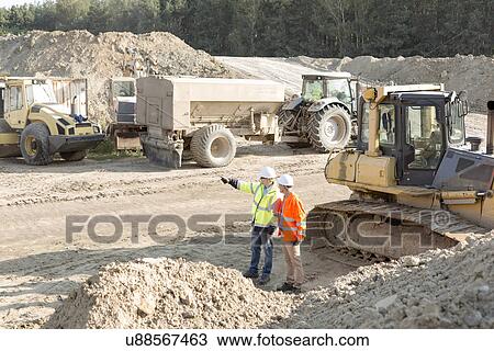 Supervisor showing something to colleague at construction site View Large Photo Image Stock Image - Supervisor showing something to colleague at construction site. Fotosearch