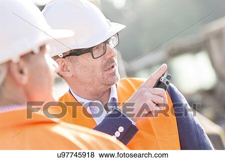 Supervisor showing something to colleague at construction site View Large Photo Image Stock Photo - Supervisor showing something to colleague at construction site. Fotosearch