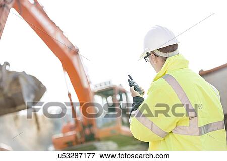 Supervisor using walkie-talkie at construction site against clear sky View Large Photo Image Stock Photo - Supervisor using walkie-talkie at construction site against clear sky. Fotosearch