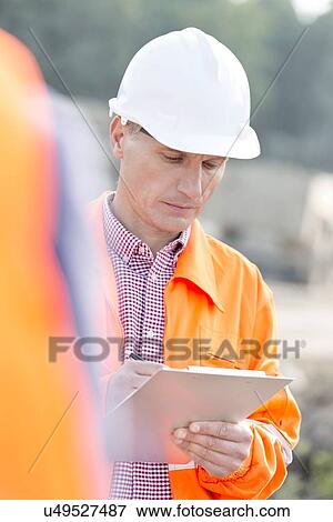 Supervisor writing on clipboard at construction site View Large Photo Image Stock Photo - Supervisor writing on clipboard at construction site. Fotosearch