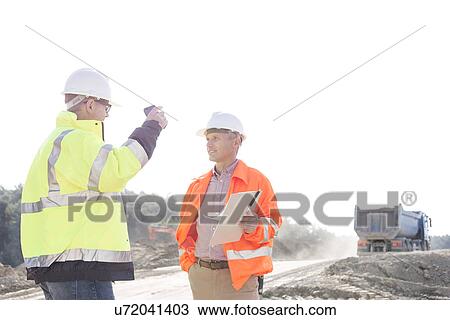 Supervisors discussing at construction site against clear sky View Large Photo Image Stock Image - Supervisors discussing at construction site against clear sky. Fotosearch