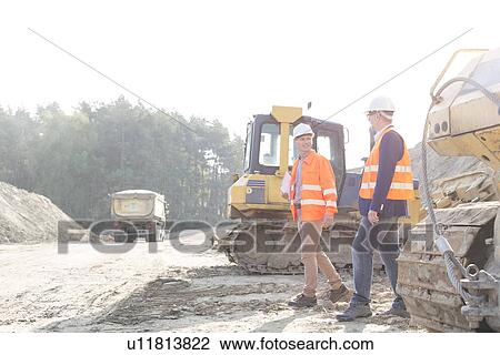 Stock Image - Supervisors walking at construction site against clear sky. Fotosearch