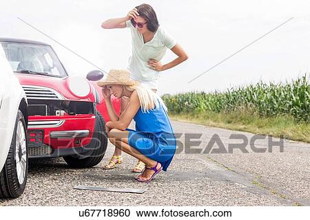 Stock Image - Tensed women looking at damaged cars on road against clear sky. Fotosearch