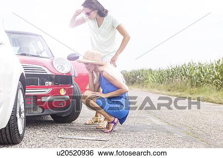 Tensed women looking at damaged cars on road against clear sky View Large Photo Image Stock Photograph - Tensed women looking at damaged cars on road against clear sky. Fotosearch