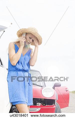 Tensed young woman using cell phone by broken down cars View Large Photo Image Stock Image - Tensed young woman using cell phone by broken down cars. Fotosearch
