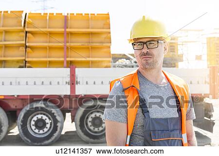 Thoughtful architect standing against truck at construction site View Large Photo Image Stock Photo - Thoughtful architect standing against truck at construction site. Fotosearch
