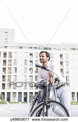 Thoughtful businessman leaning on bicycle outdoors View Large Photo Image Stock Image - Thoughtful businessman leaning on bicycle outdoors. Fotosearch