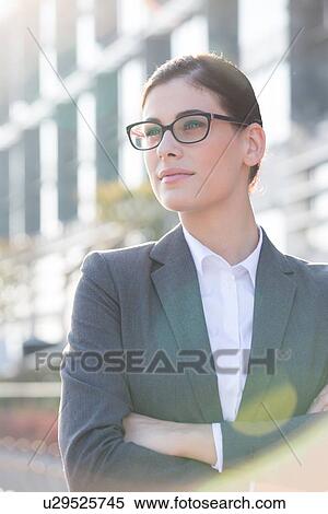 Stock Photography - Thoughtful businesswoman standing arms crossed outdoors. Fotosearch